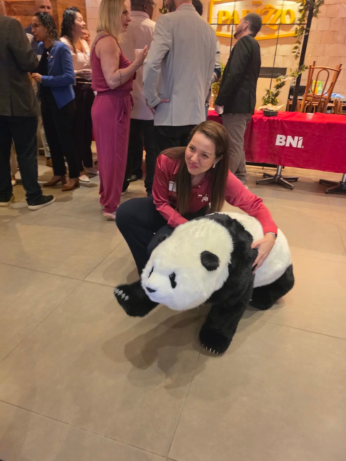Convidada agachada ao lado do panda robô, posando para uma foto durante o café da manhã