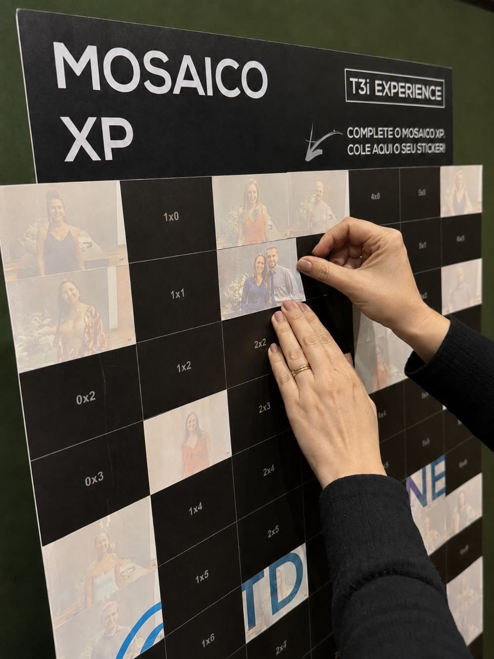 Participante colando a própria foto adesiva na posição indicada do painel do Mosaico XP