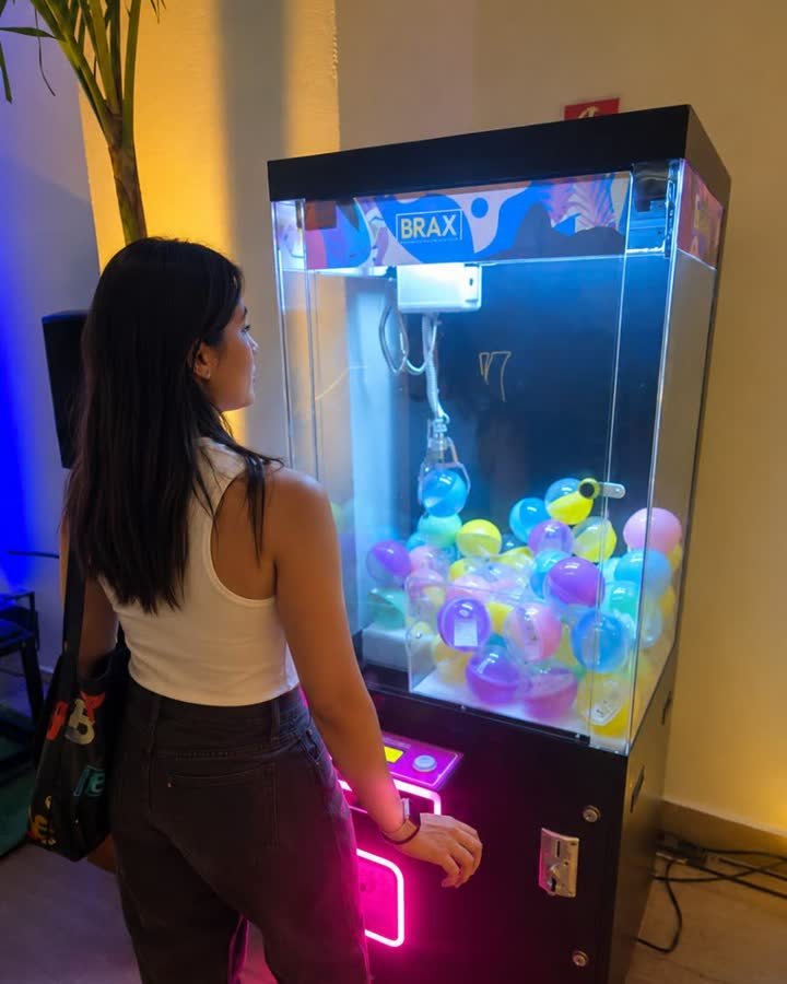 Participante em frente à máquina de garra personalizada com a marca